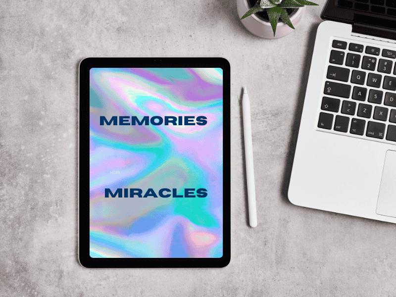 An iPad showing the words Memories and Miracles over a dreamy background. The device is on a table and next to it an Apple pen and a macbook. There's also a flower pot with a cactus